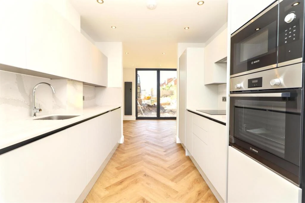 Light kitchen with integrated appliances and herringbone flooring